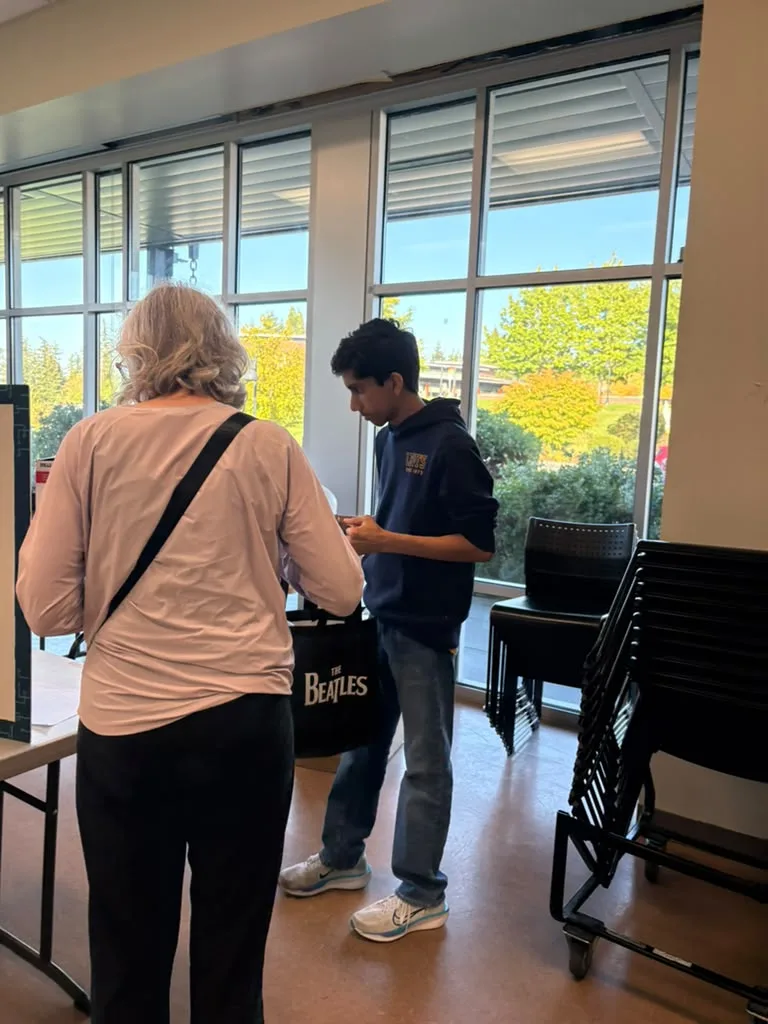 A visitor speaking with a volunteer at collection tables