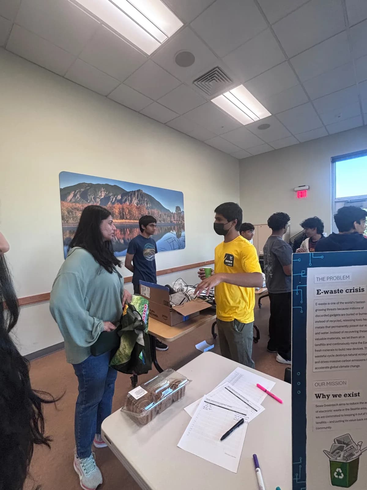 A volunteer speaking with a visitor across the collection table
